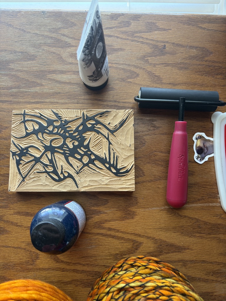Hand-carved relief printing block surrounded by carving and printing tools