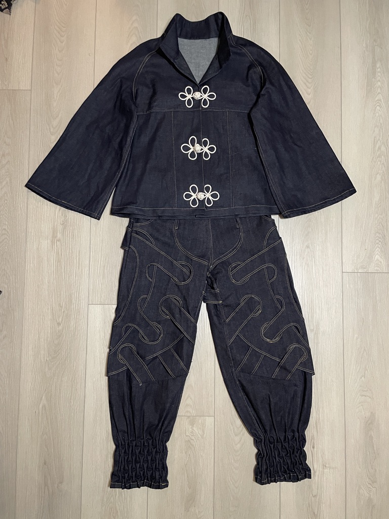 The complete Tension System 01 jacket and jeans arranged as a flat lay with oversized white frog closures